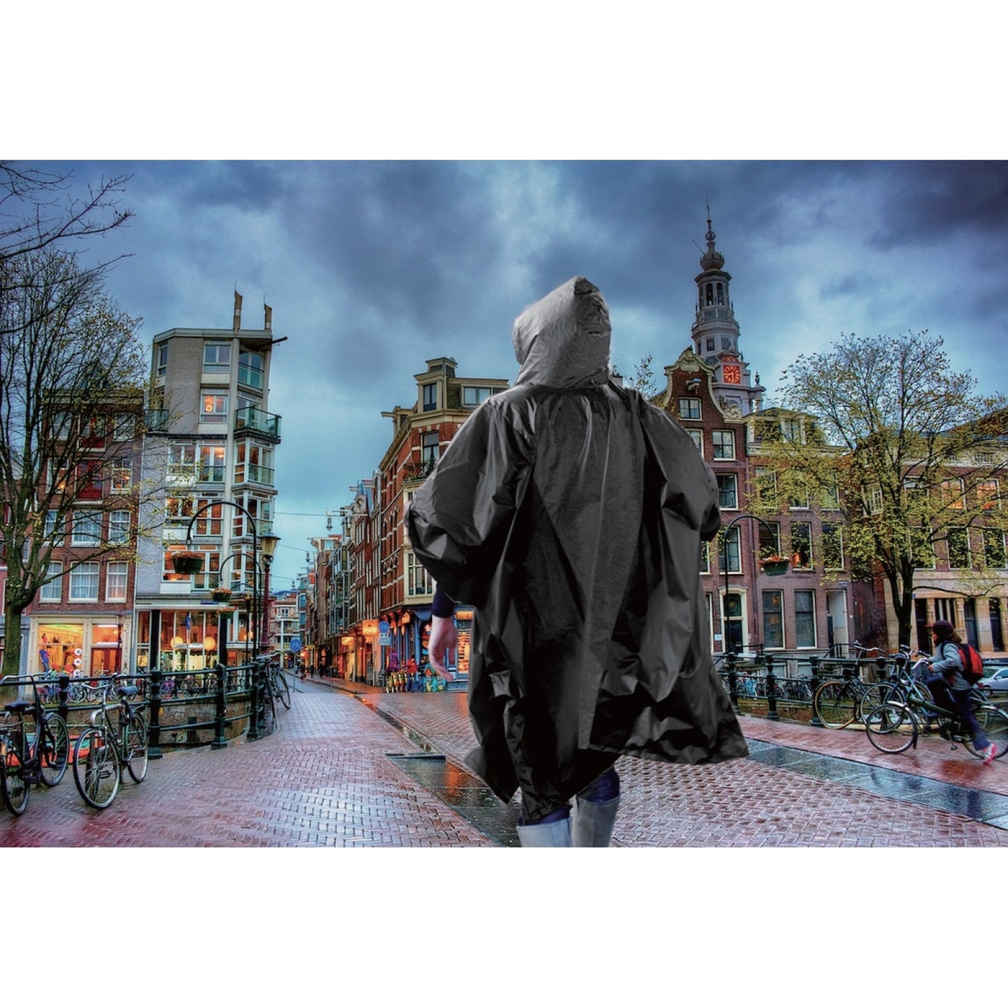 Person mit schwarzem Regenponcho geht bei bewölktem Himmel durch eine nasse Stadtstraße mit Fahrrädern und Gebäuden im Hintergrund.