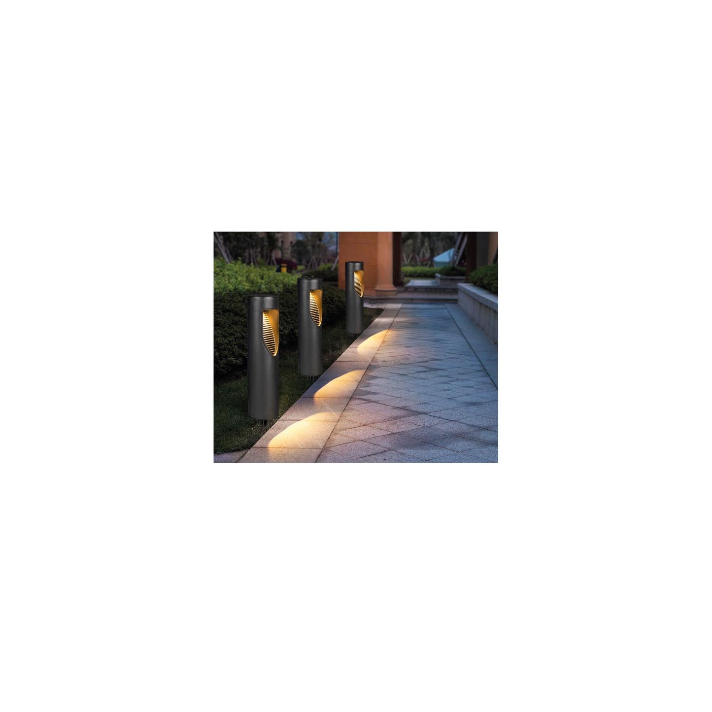 Drei schwarze LED-Gartenleuchten mit schildförmiger Lichtöffnung stehen entlang eines gepflasterten Weges und werfen bei Dunkelheit einen gebündelten Lichtkegel auf den Boden.