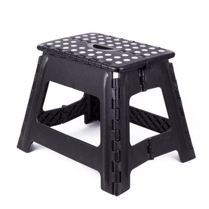 Schwarzer, klappbarer Kunststoffhocker mit weißen Punkten auf der Sitzfläche und Grifföffnung in der Mitte, auf weißem Hintergrund.