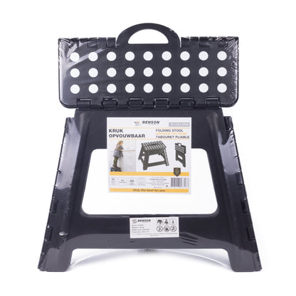 Schwarzer, zusammengeklappter Klapphocker mit Etikett auf der Vorderseite, das Produktinformationen und ein Foto des Hockers beim Einsatz zeigt.