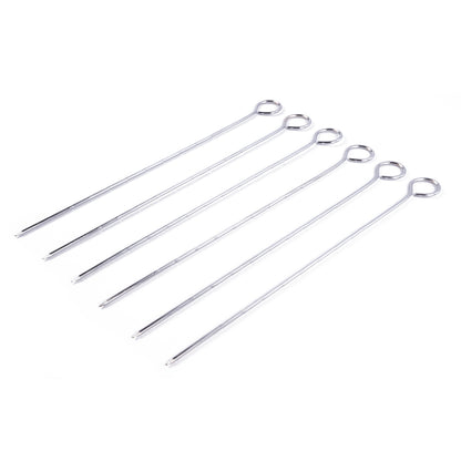 Sechs silberfarbene Grillspieße aus Metall, schräg nebeneinander auf weißem Hintergrund liegend. Die spitzen Enden zeigen nach links unten, die Schlaufen nach rechts oben.