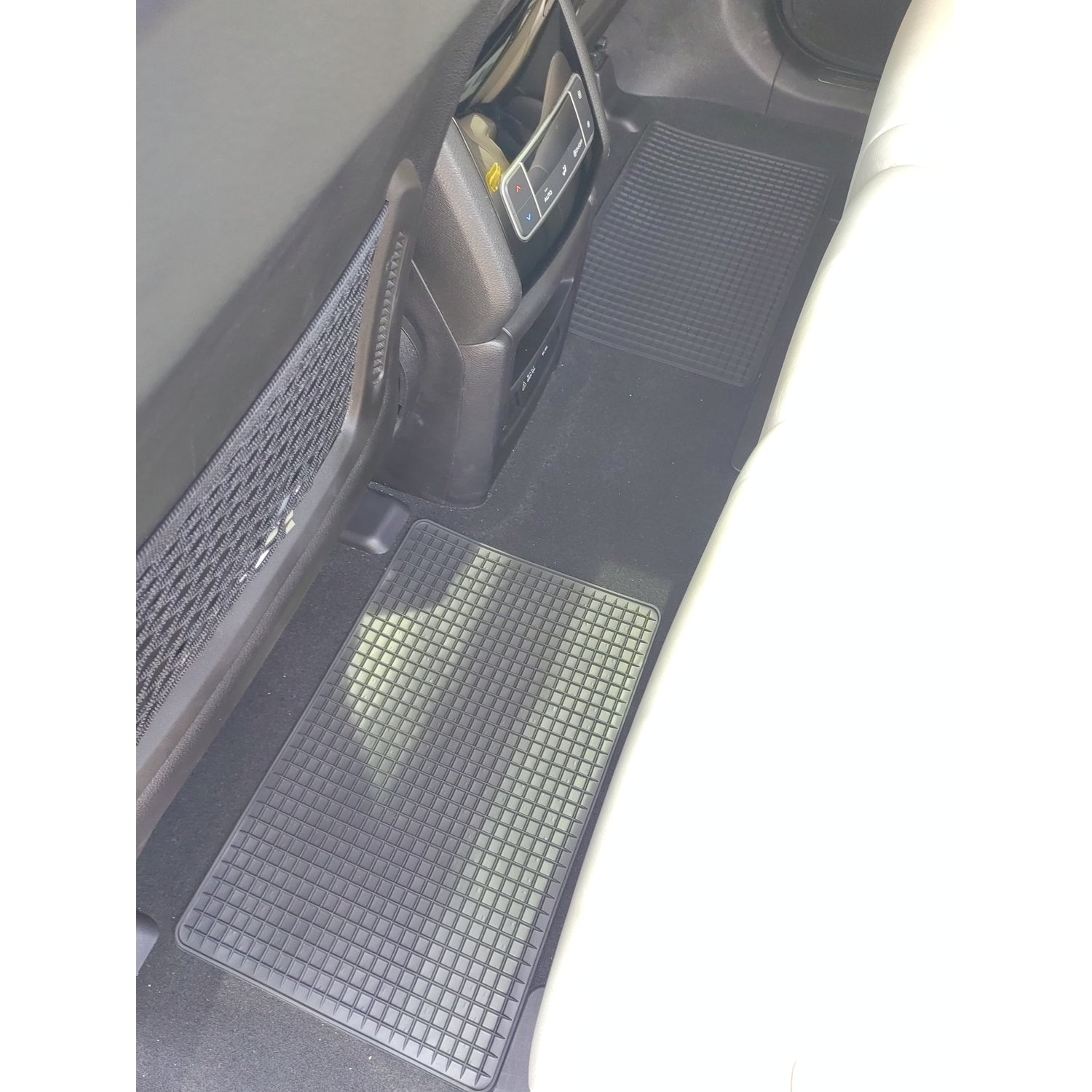 Zwei schwarze Gummimatten mit Rasterstruktur auf dem Fahrzeugboden im hinteren Fußraum eines Autos platziert.