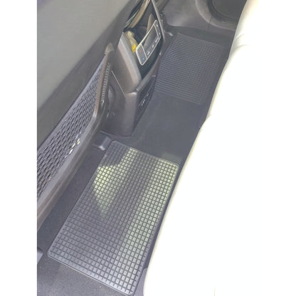 Zwei schwarze Gummimatten mit Rasterstruktur auf dem Fahrzeugboden im hinteren Fußraum eines Autos platziert.