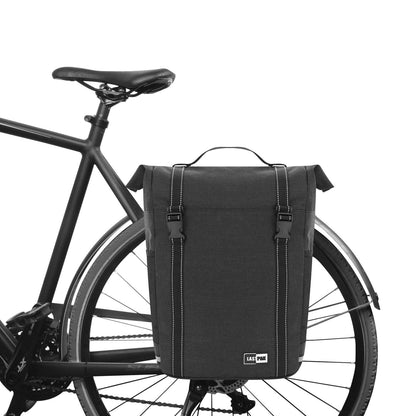 Schwarze Fahrradtasche mit zwei Klickverschlüssen am Gepäckträger eines schwarzen Fahrrads montiert.