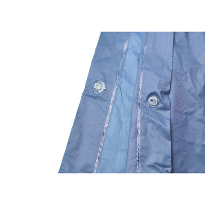 Nahaufnahme eines hellblauen Regenponchos mit Druckknöpfen entlang der Seitennaht, die zum Verschließen dienen.