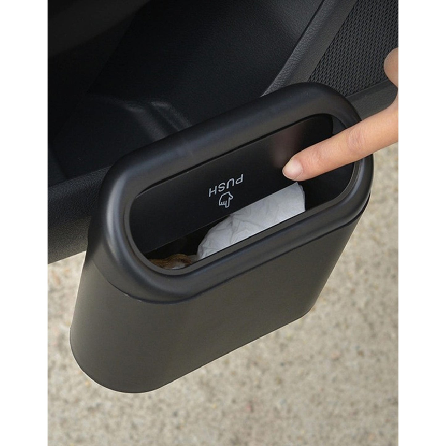 Schwarzer Auto-Mülleimer mit Druckdeckel, an der Türverkleidung befestigt, eine Hand drückt den Deckel zum Einwerfen von Müll.