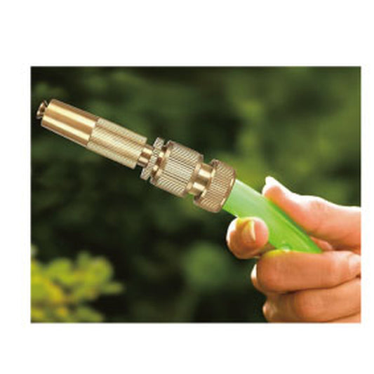 Hand hält grünen Gartenschlauch mit montierter verstellbarer Messing-Spritzdüse, Hintergrund unscharf mit grünem Laub.