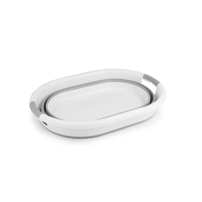 Zusammengeklappter ovaler Wäschekorb in Grau und Weiß mit integrierten Grifföffnungen, flach liegend auf weißem Hintergrund.