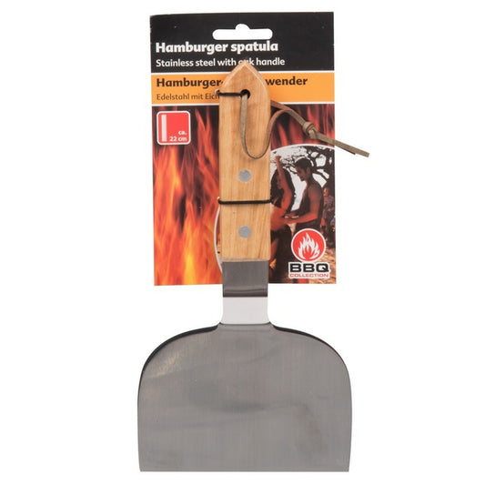 Hamburger-Wender aus Edelstahl mit breitem, abgerundetem Blatt und Holzgriff mit Lederband. Der Wender ist an einer Verpackung mit Flammenmotiv und Produktinformationen befestigt und wird hängend präsentiert.