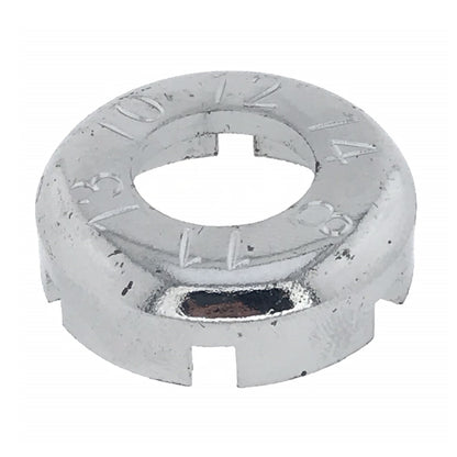 Rundes, silberfarbenes Metallwerkzeug mit zentraler Öffnung, mehreren rechteckigen Aussparungen am Rand und eingravierten Zahlen auf der Oberseite, auf weißem Hintergrund.