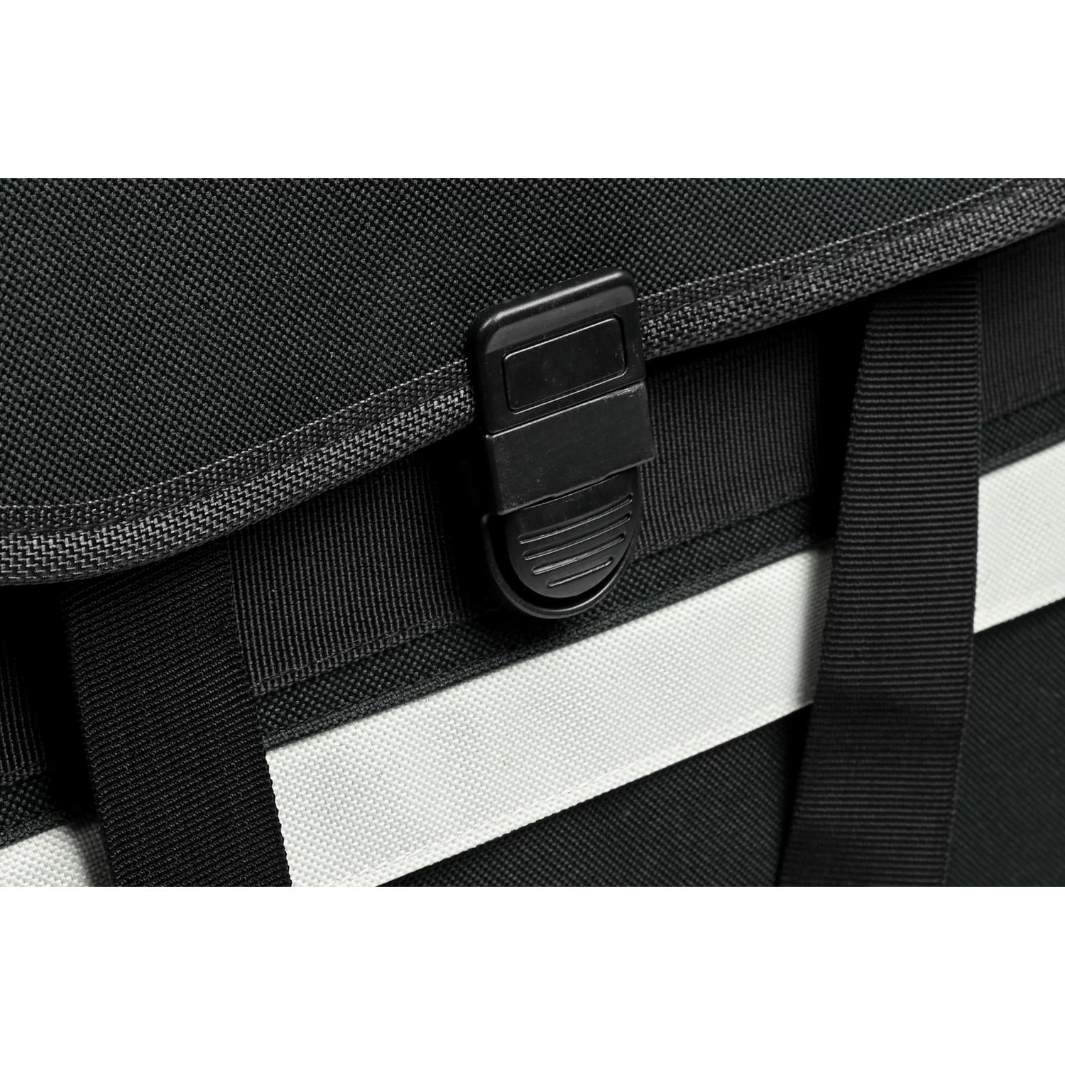 Detailaufnahme des schwarzen Steckverschlusses an der Vorderseite der Fahrradtasche mit grauem Reflektorstreifen darunter.